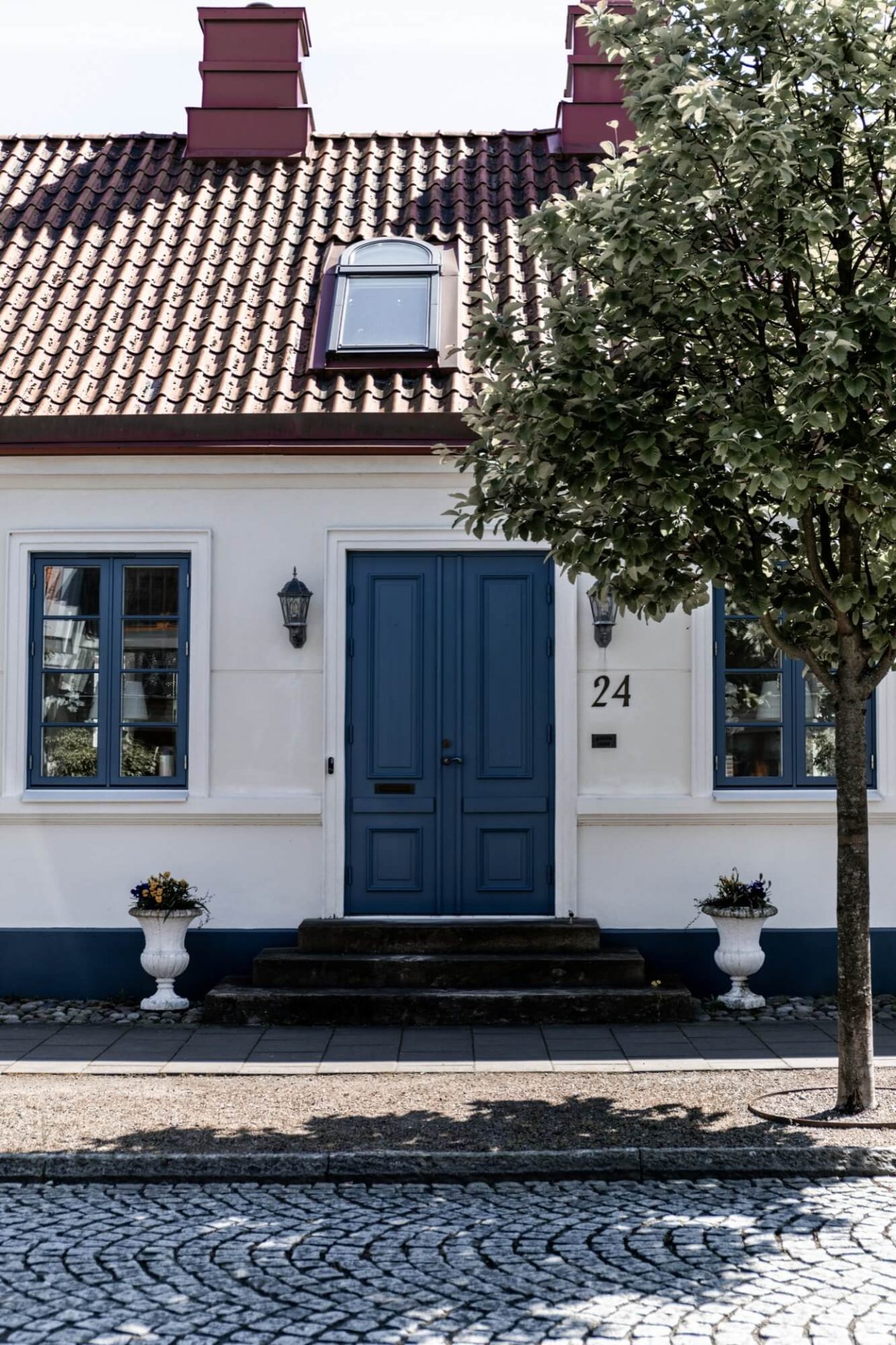 Den vita putsen på husets fasad, de blå detaljerna kring dörr och fönster samt kullerstenen på trottoaren skapar en klassisk estetik